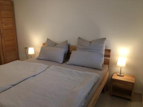 a bedroom with two beds with white pillows and two lamps at Ferienwohnung Gluiber in Beuren