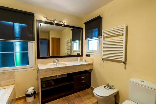 a bathroom with a sink and a toilet and a mirror at Villa Arena Blanca in Sant Lluis