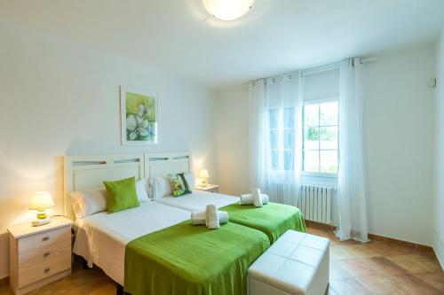 a bedroom with two beds with green sheets at Villa Arena Blanca in Sant Lluis