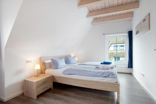 a white bedroom with a bed and a window at Ferienhaus Seestern in Dranske