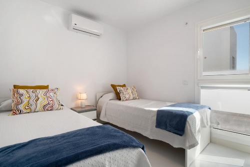 two beds in a white room with a window at Ocean 1 in La Santa