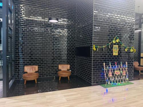a room with two chairs and a wall with black tiles at Chamber Haven KLCC in Kuala Lumpur