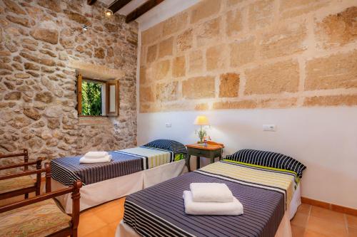 two beds in a room with a stone wall at Finca So na Sopa in Artá