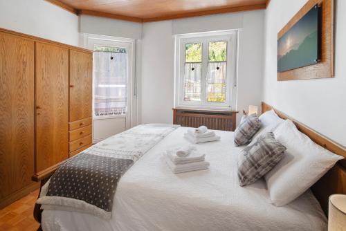 a bedroom with a large white bed with two windows at Dimora Il Feudo - Predazzo in Predazzo