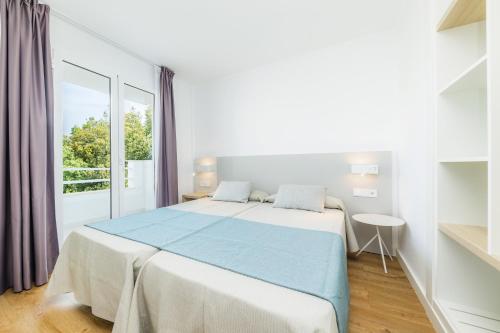 a white bedroom with a large bed and a window at Apartament Massanet 2a in Canyamel