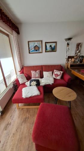 a living room with a red couch and a table at Ferienwohnung Älple im Sonnenpark in Bad Hindelang