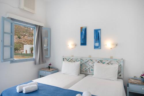 a white bedroom with a bed and a window at Pico Bello Patmos 22 in Patmos
