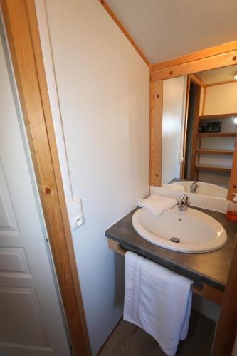 une salle de bain avec un lavabo et un miroir dans l'établissement Chalets de la Plaine, à Villebret