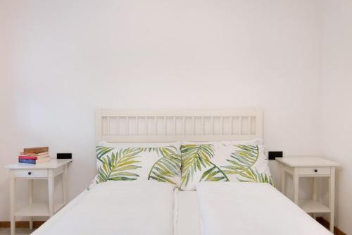 a bedroom with a white bed with two white tables at La villa del lago in giardino in Colico