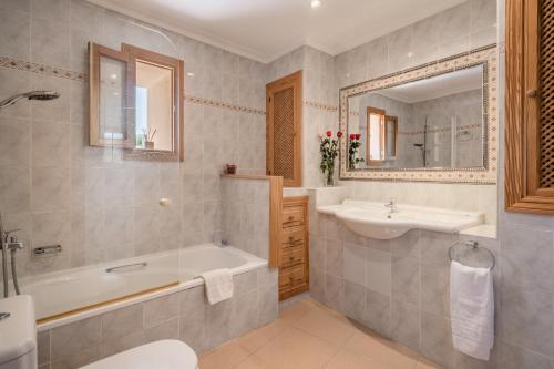 a bathroom with a tub and a sink and a mirror at Ca la Pradina in Pollença
