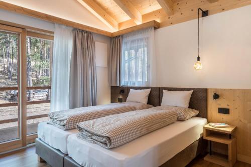 two beds in a bedroom with a large window at Les Ciases Chalets Dolomites Apt 4 in San Vigilio Di Marebbe