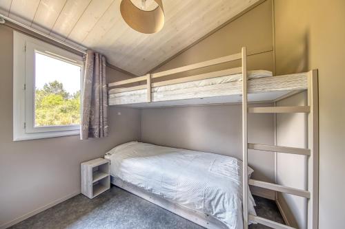 a small bedroom with bunk beds and a window at Chalet parc nature océan in Hourtin