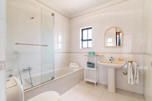 a white bathroom with a tub and a sink at Casa das Areias in Porches