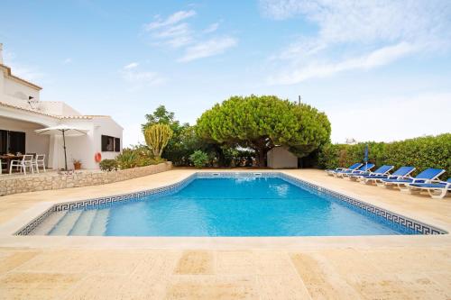 a swimming pool in a villa with chairs and trees at Casa das Areias in Porches