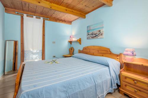 a bedroom with a wooden bed with a blue bedspread at Residence Asfodeli E4 in San Teodoro