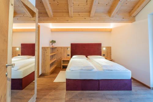 two beds in a room with wooden ceilings at App. Erta - Ciasa Lavarella in San Vigilio Di Marebbe