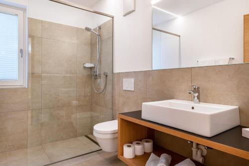 a bathroom with a sink and a shower and a toilet at Ferienwohnungen Karin - Gala in Termeno