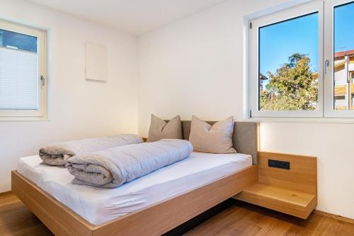 a bed in a room with two windows at Ferienwohnungen Karin - Gala in Termeno