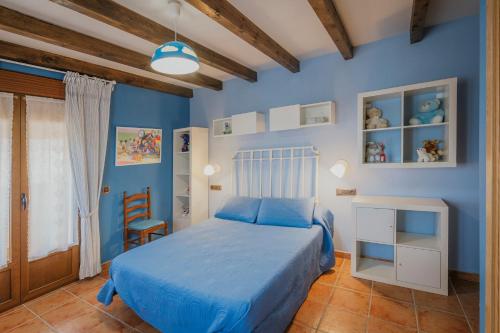 a blue bedroom with a bed and a chair at Casa Las Tres Coteras in Muñopedro