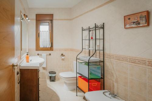 a bathroom with a toilet and a sink and a shelf at Casa Las Tres Coteras in Muñopedro