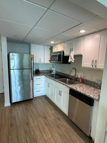 a kitchen with white cabinets and a stainless steel refrigerator at Stunning Water View Suite in Fort Myers