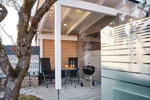 a patio with a grill and a table and a tree at Ferienhaus am Millibach in Wehingen