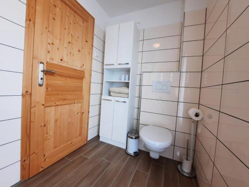 a bathroom with a toilet and a wooden door at Ferienhaus Emelie Geiseltalsee in Mücheln