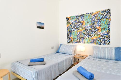 a room with two beds and a painting on the wall at Appartamento Pini in Cala Gonone