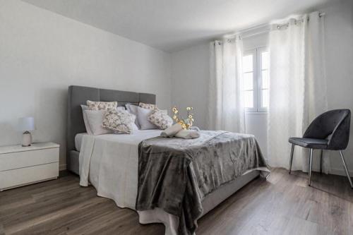 a white bedroom with a bed and a chair at Sweet Home Madeira in Camacha