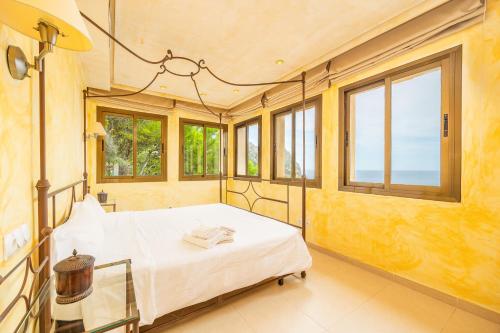 a bedroom with a bed in a room with windows at Villa Cala Llamp in Port d'Andratx