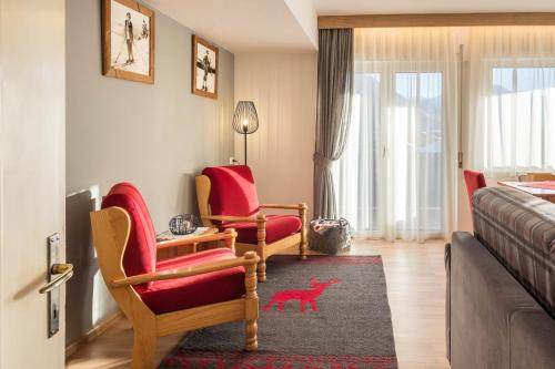 a living room with red chairs and a bed at Ciasa De Marugiana in Gardeccia - San Giovanni di Fassa