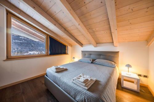 a bedroom with a bed and a large window at La Pratolina Attico in Castello di Fiemme