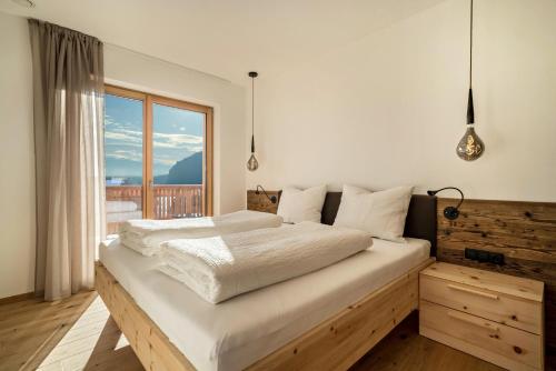 a bedroom with a large bed and a large window at Apt Fichte - Nockerhof in Andrian