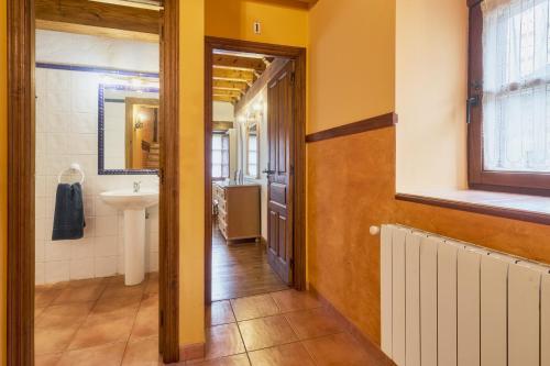a hallway of a bathroom with a sink and a mirror at El Serenal in Santa Maria de Valdeón