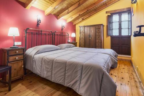 a bedroom with a large bed with red walls at El Serenal in Santa Maria de Valdeón