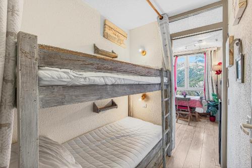 two bunk beds in a room with a table at Cosy 4p, Pied des Pistes, Pra Loup in Uvernet