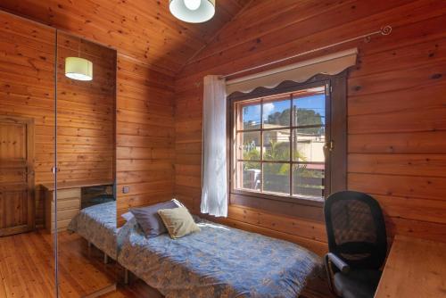 a bedroom with a bed in a wooden room with a window at Villa Tanqueta in Santa Brígida
