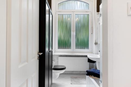 a bathroom with a toilet and a window at Villa am Weinberg in Wiesbaden