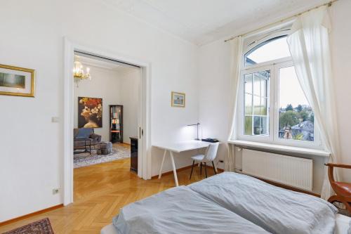 a bedroom with a bed and a desk and a window at Villa am Weinberg in Wiesbaden