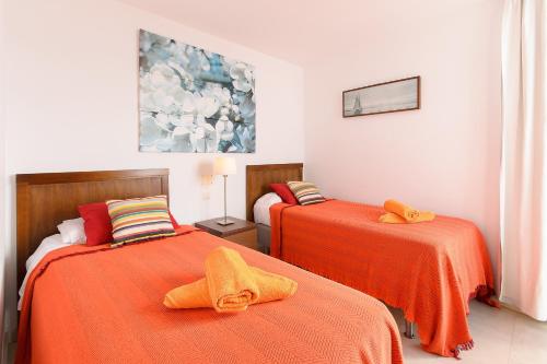 two beds with orange sheets in a room at Luis ii in Puerto del Carmen