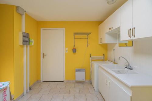 a kitchen with yellow walls and a white sink at Maison Individuelle, Royan Centre in Royan