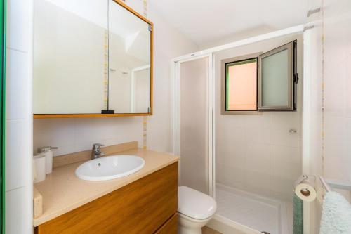 a bathroom with a sink and a toilet and a mirror at Sa Marina in Alcudia