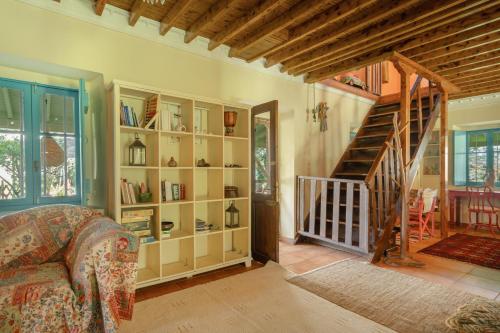 a living room with a book shelf and a staircase at Lefkadas Bohemian Cottage in Lefkada