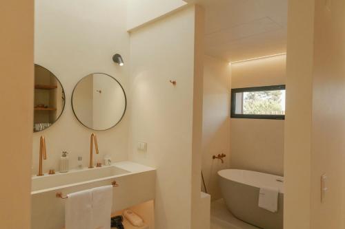 a bathroom with a tub and a sink and a mirror at M Villa Comporta Retreat in Carvalhal