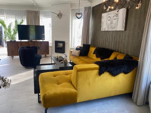 a living room with a yellow couch and a television at HOLTINGERHUYS Havelte- Giethoorn! Tegen betaling Wellness!!! in Havelte