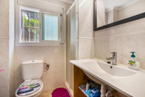 a bathroom with a toilet and a sink and a window at La Finca Moraira in Teulada