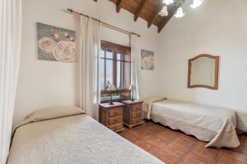 a bedroom with two beds and a mirror and a window at El Almendro in Tesbabo