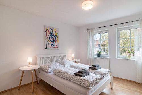 ein Schlafzimmer mit einem Bett, zwei Tischen und zwei Fenstern in der Unterkunft Aposto Apartments 2 in Oberderdingen