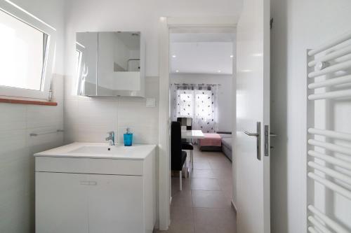 a white kitchen with a sink and a dining room at Adelino Guest House in Olhão