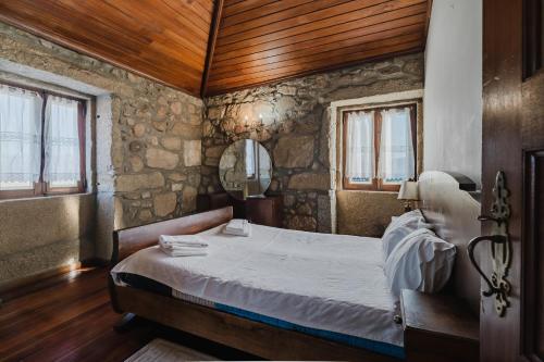 a bedroom with a bed with a wooden ceiling and windows at Quinta Das Regadas in Rendufe